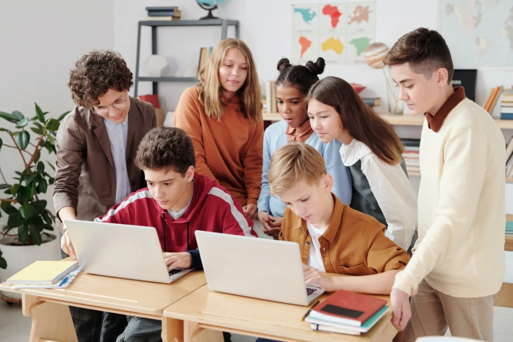 Kinder stehen um Computer in der Schule