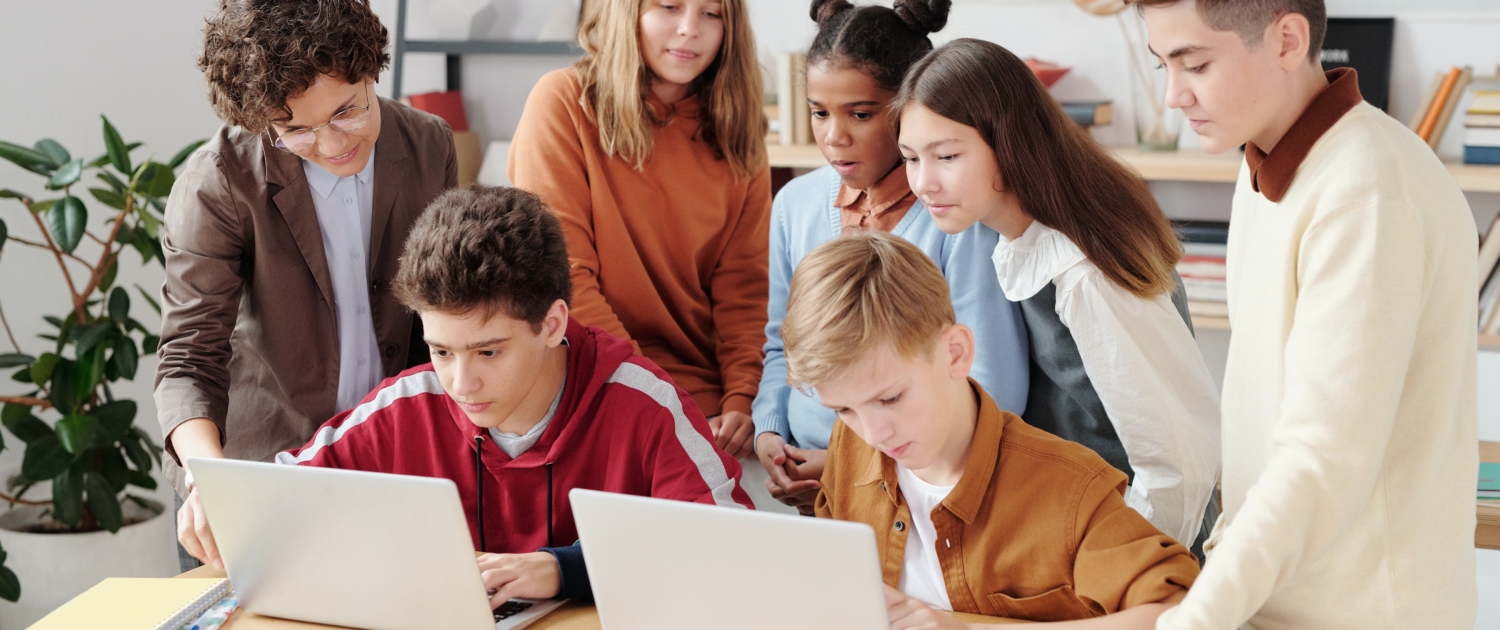Kinder stehen um Computer in der Schule