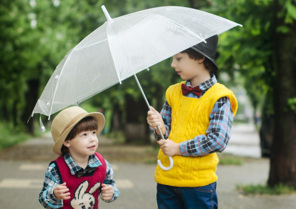 Zwei Kinder unter einem Regenschirm.
