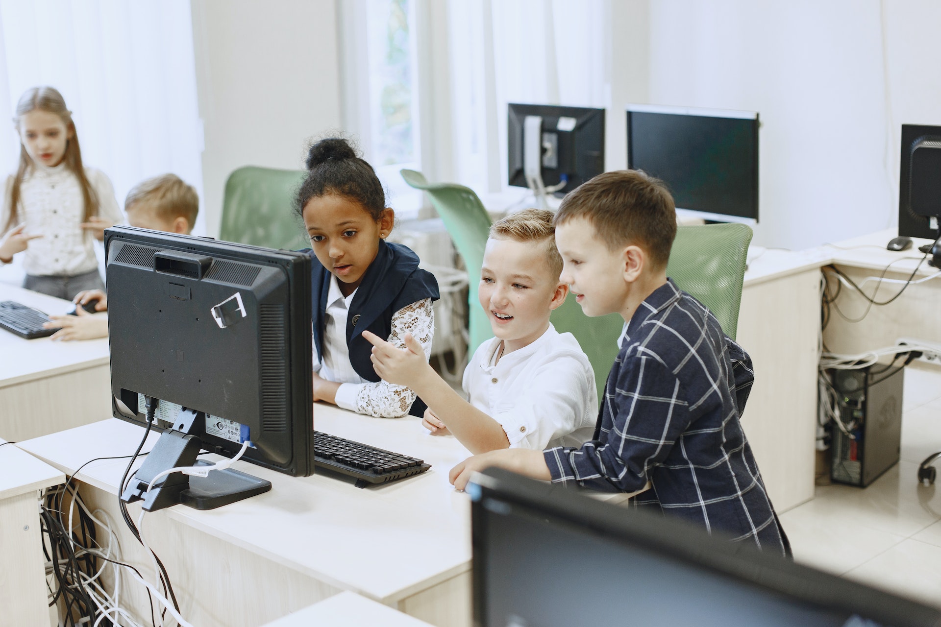 Kinder sitzen gemeinsam vor einen Bildschirm und ein Schüler zeigt darauf.