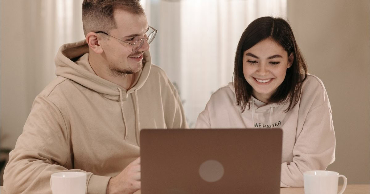 Zwei Erwachsene vor einem Laptop sitzend
