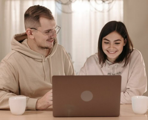 Zwei Erwachsene vor einem Laptop sitzend