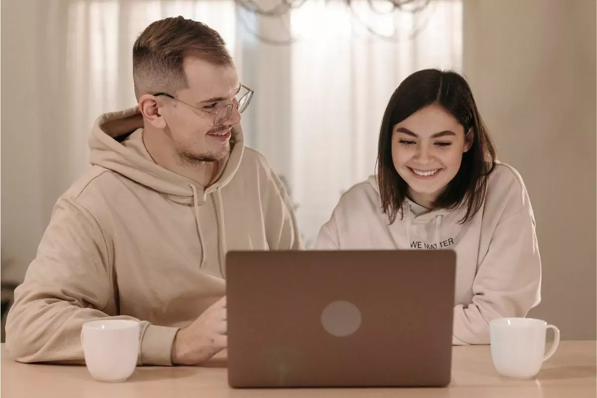 Zwei Erwachsene vor einem Laptop sitzend