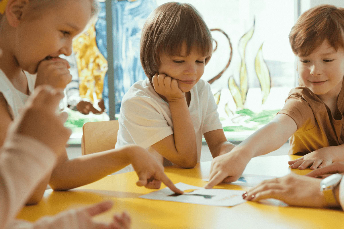 Lehrerin sitzt mit einigen Schüler*innen zusammen. Alle lachen.